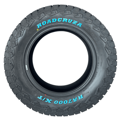 A single black all-terrain tyre with aggressive tread, featuring the brand name 'ROADCRUZA' and model 'RA7000 XT' printed in bright cyan blue on the sidewall, isolated on a white background.