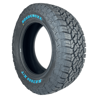 A single off-road tire shown at a three-quarter angle on a plain white background. The sidewall features the brand name 'ROADCRUZA' in blue lettering and the model 'RA7000 X/T' in white lettering.