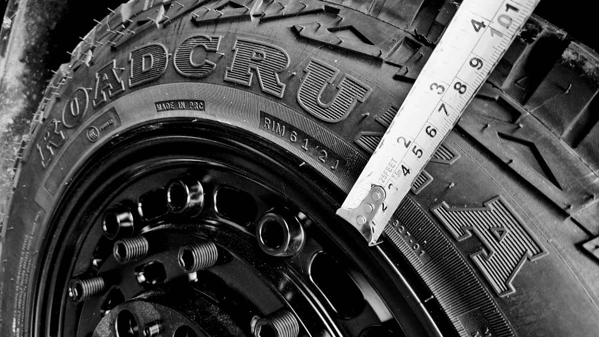 Plus sizing black and white image of tape measure measuring tyre sidewall